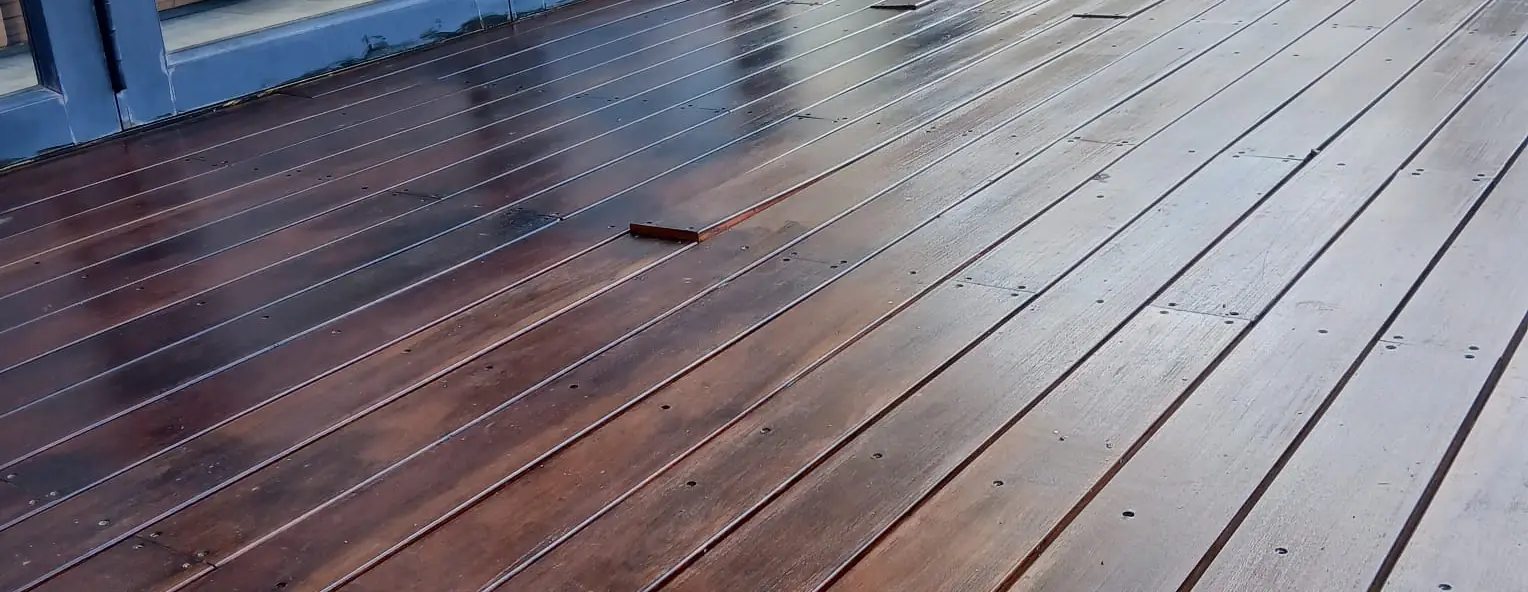 Dark oiled hardwood deck running out from a home at dusk, built by Impi Teak