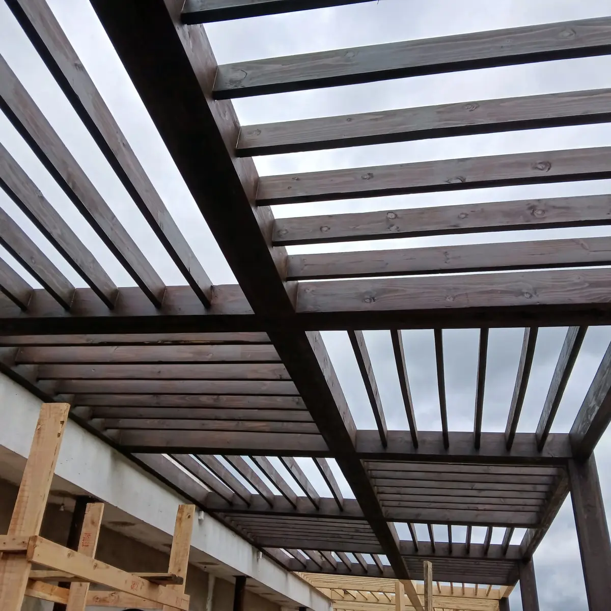 Dark stained timber pergola structure over a Midrand patio, fabricated by Impi Teak